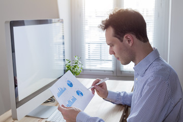 Businessman working with financial reports and computer in modern interior