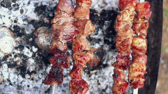 Grilled meat. Man takes off skewers with cooked meat from grill. BBQ meat ready. Barbeque meat. Tasty shish kebab on skewers. Grilled barbecue meat. Grilled food for picnic. Prepared barbecue food
