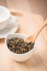  dry tea leaf in ceramic bowl on wood background
