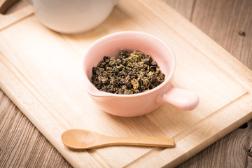  dry tea leaf in ceramic bowl wit whith pot on wood background