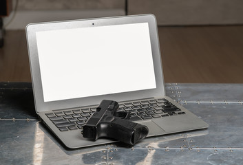 Black pistol on the keyboard of laptop
