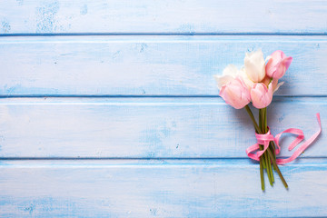 Fototapeta na wymiar Bunch of white and pink spring tulips with pink ribbon on blu