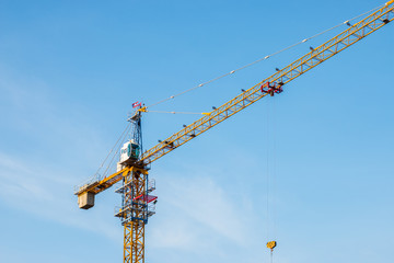 Crane lifting concrete mixer container against blue sky