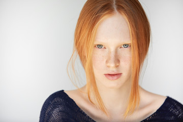 Close up portrait of happy beautiful redhead girl with perfect healthy skin wearing casual clothes, looking and smiling at the camera with penetrating blue eyes. Human face expressions and emotions