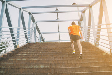 Urban jogger on the staircase of a bridge.
