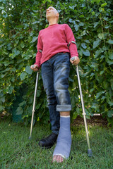 Young man with a leg cast in a garden