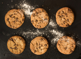 Freshly baked chocolate chips cookies with flour, on baking tray