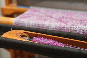 Weaving shuttle with thread on the lilac warp