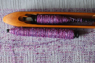 Weaving shuttle with thread on the lilac warp