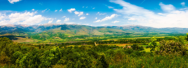 Fototapeta na wymiar Panorama of green valley in the Pyrenees Mountains on sunny day with blue skies.