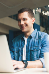 Cheerful male worker is typing on notebook