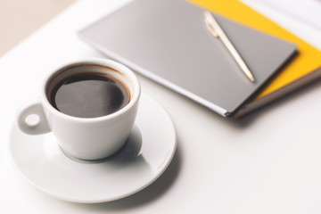 Mug of hot drink and writing-pads on desk