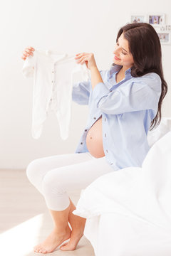 Beautiful expectant mother is showing small clothing