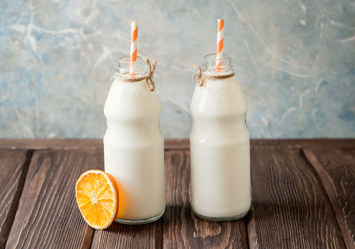 Milk bottles with drinking straw on a wooden background