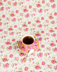 Antique tea cup full of tea on floral background