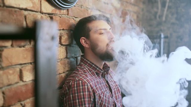 young stylish man with electronic cigarette vaping