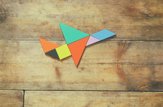 plane made from tangram puzzle on wooden background