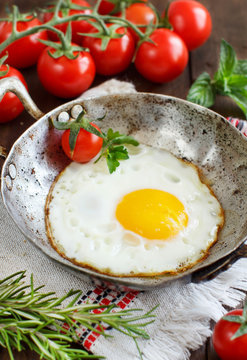 Fried egg with tomatoes and herbs n a old frying pan