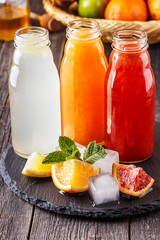Fresh citrus juices on a dark wooden background.