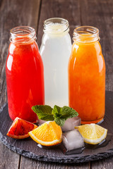 Fresh citrus juices on a dark wooden background.