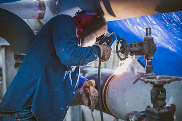 Welder is welding pipe on construction site