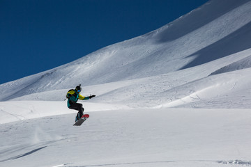 Man snowboarder snowboarding on fresh white snow on ski slope on Sunny winter day