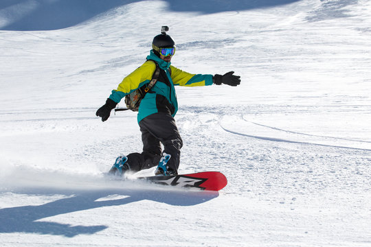 Man snowboarder snowboarding on fresh white snow on ski slope on Sunny winter day