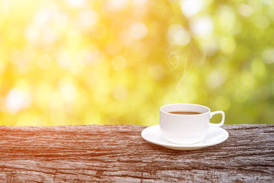 coffee cup on wooden table over abstract nature background.