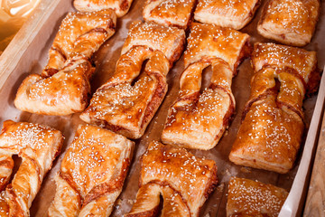 Delicious Puff pastry with cheese filling and sesame seeds on shelf in Bakery shop. Pastries and bread in a bakery