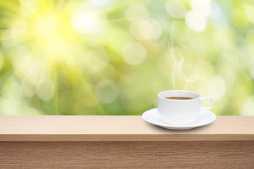 coffee cup on wooden table over abstract nature background.