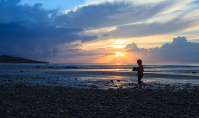 Fototapeta premium boy walking on the sandy beach on sunset 