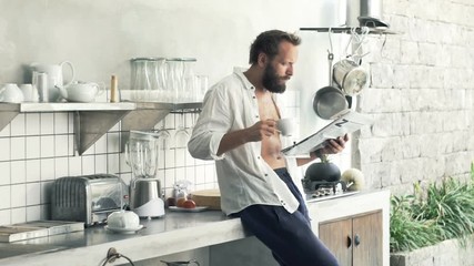 Young man reading newspaper and drinking coffee in kitchen at home
- Powered by Adobe