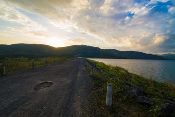 Sunset over dam rural road with mountain