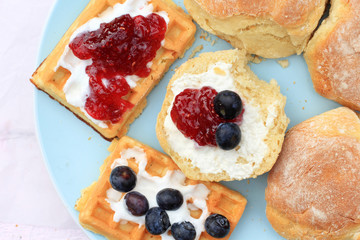 Fresh Scottish scones and belgian waffles with cream and raspberry jam and blueberries