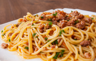 spaghetti with vegetables and minced meat in a plate on wooden table