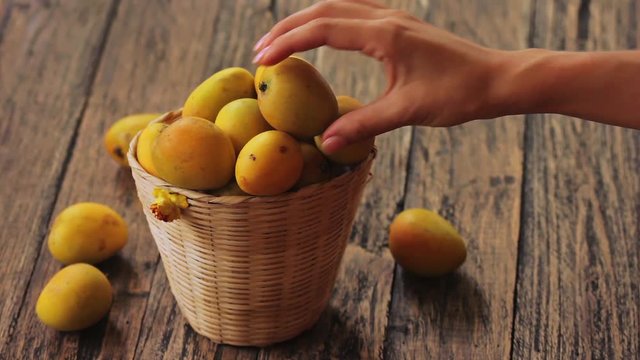 Female hand taking one mango from the basket with mangoes