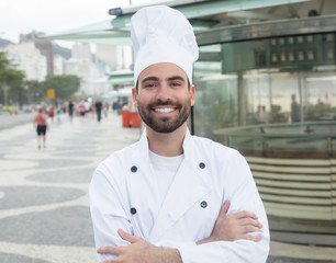 Lachender Chefkoch vor seinem Restaurant