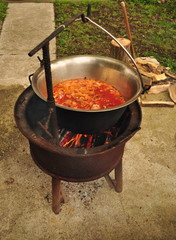 Traditional Goulash soup is boiling in the a cauldron