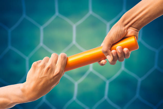 hands passing a relay baton on on soccer goal net background with vintage color tone effect.