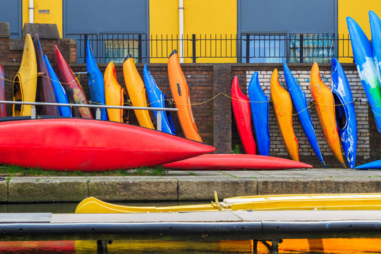 Row of colourful kayaks leaning against brick wall on the Regent’s canal in London