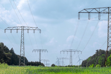 Elektrotrasse mit Hochspannungsleitungen, Masten und Windkraftwerken mitten in der Natur