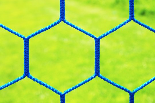Detail of yellow blue crossed soccer football net with grass