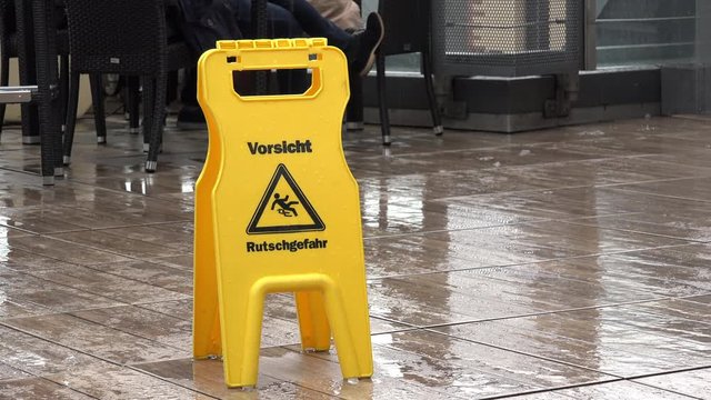 German caution sign in the rain warning people of slippery floor.
