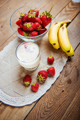 Strawberry and banana smoothie in a glass on blue wooden table.