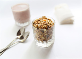 Granolai is for the breakfast in the transparent glass with yogurt, napkins and spoons on white background