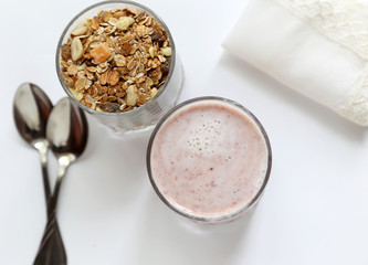 Granolai is for the breakfast in the transparent glass with yogurt, napkins and spoons on white background