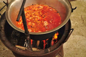 Traditional Goulash soup is boiling in the a cauldron