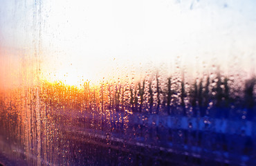water drops on the glass of the train on the background of the setting sun railroad