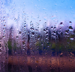 water drops on the glass of the train on the background of the setting sun railroad