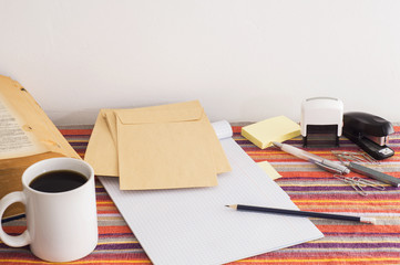 Workplace in vintage style: envelopes, notebook, book, stationery and a cup of coffee.